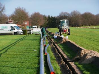 Installation eines Sportplatzbewässerungssystems mit Rohren auf einem grünen Spielfeld